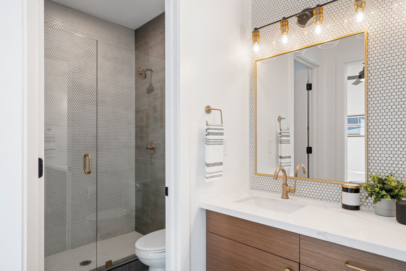 Finished bathroom with penny tile walls, brass fixtures, and walnut vanity